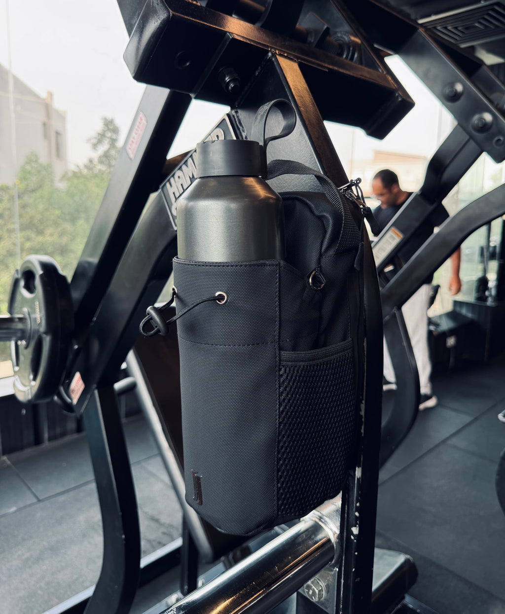Waterproof magnetic gym bag holding a large bottle on gym equipment